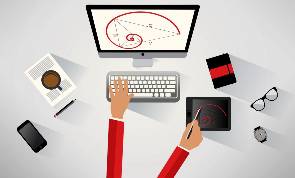 A businessperson at their desk using a desktop and tablet.