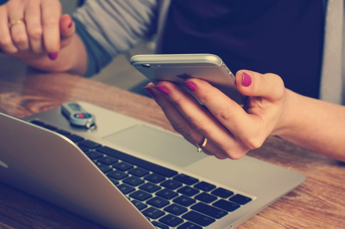 A woman using a laptop and smartphone.