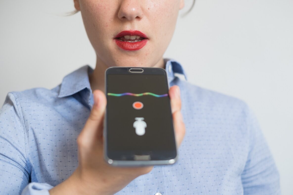 A woman speaking into a smartphone.
