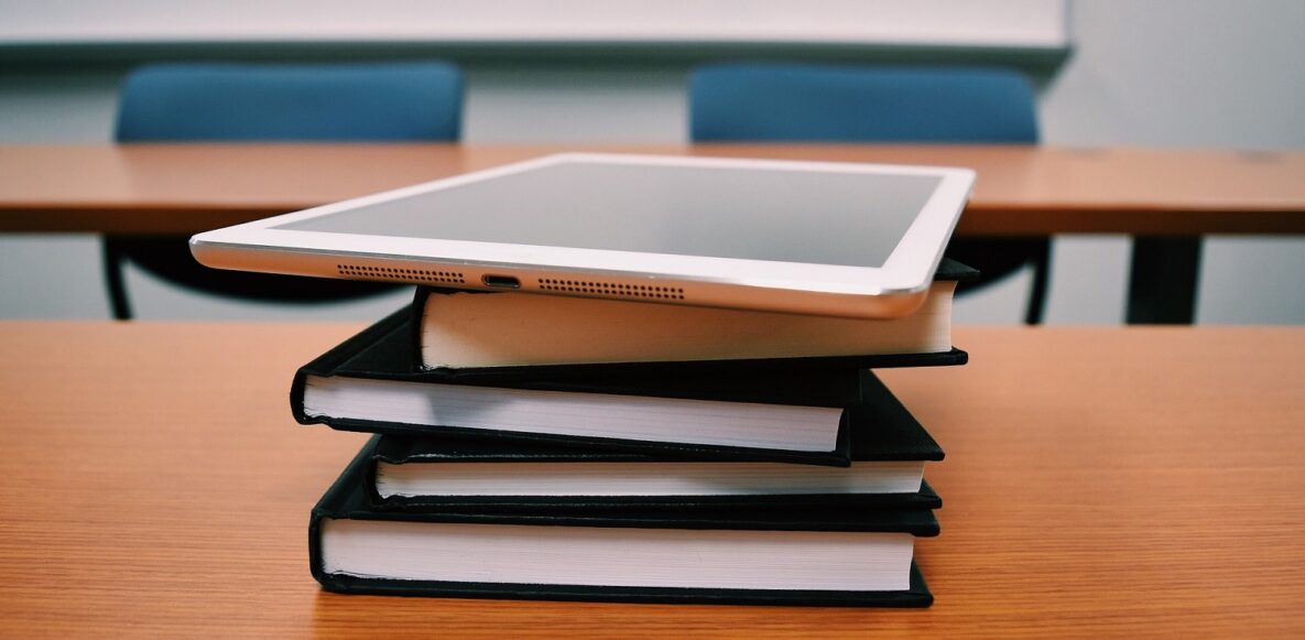 A tablet stacked on top of books.