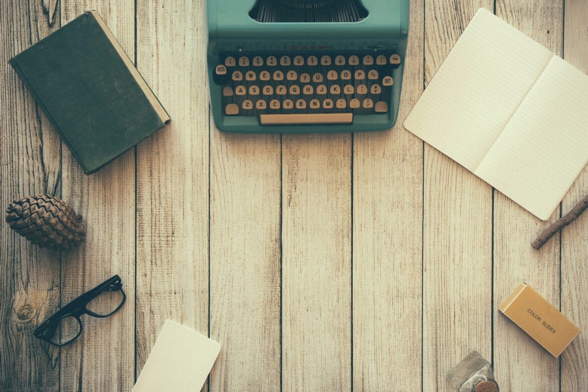 A typewriter, paper, book, and pen.