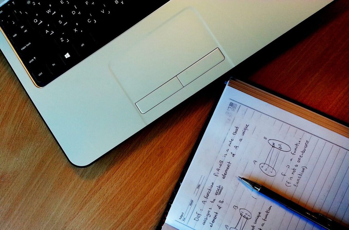 A close up of a math text and laptop.
