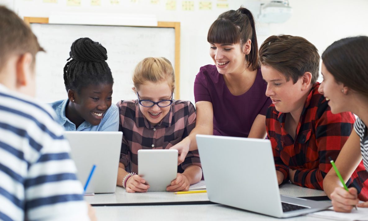 Students and their teacher using tablets and laptops in the classroom.