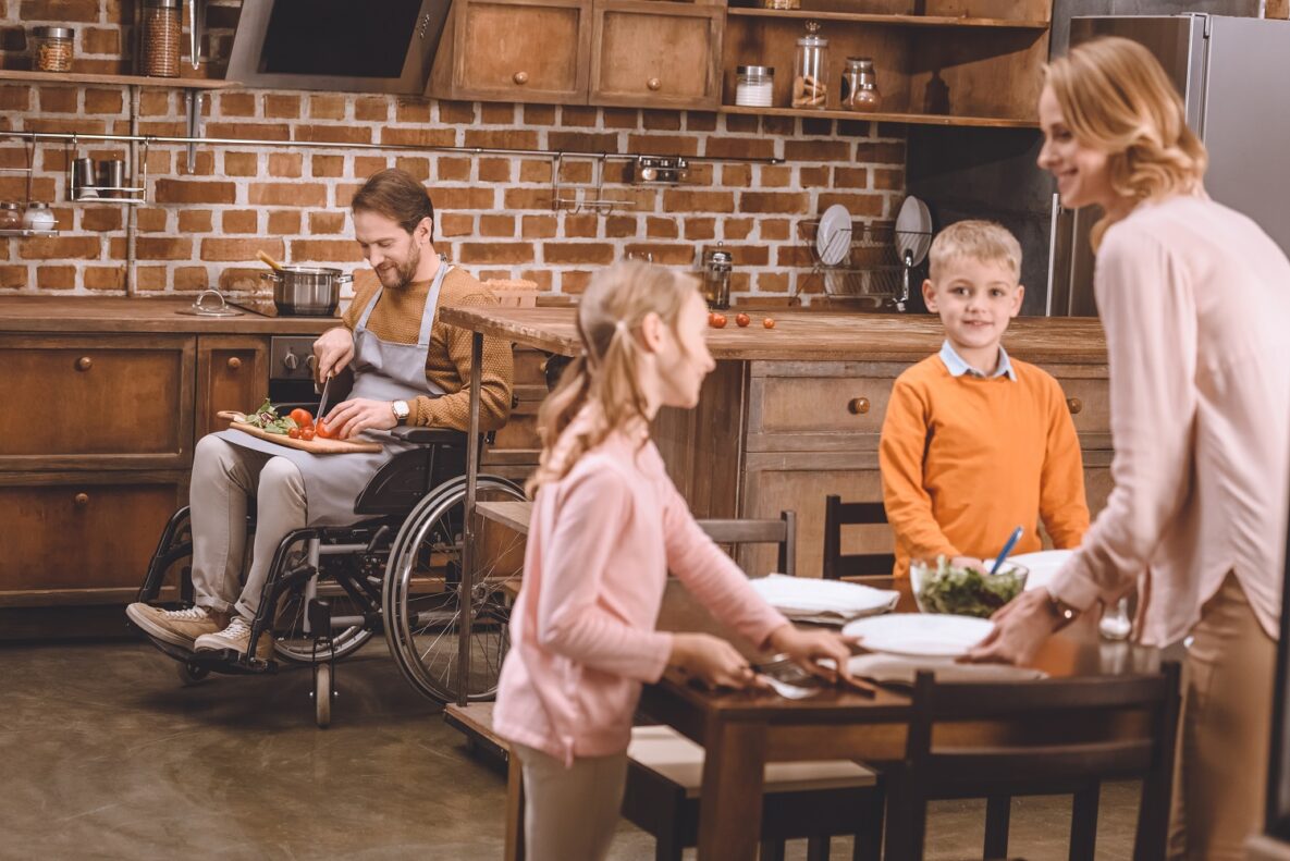 A man in a wheelchair cutting vegetables.