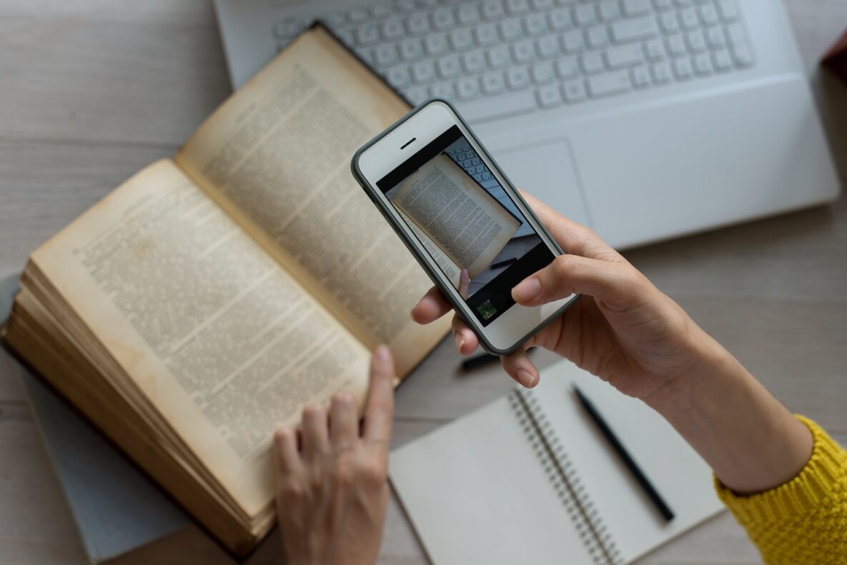 A woman taking a picture of a book using OCR.