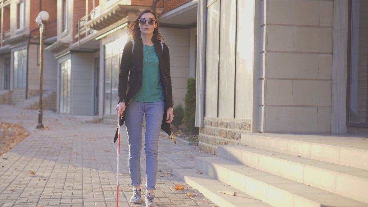 A blind woman walking with a cane.