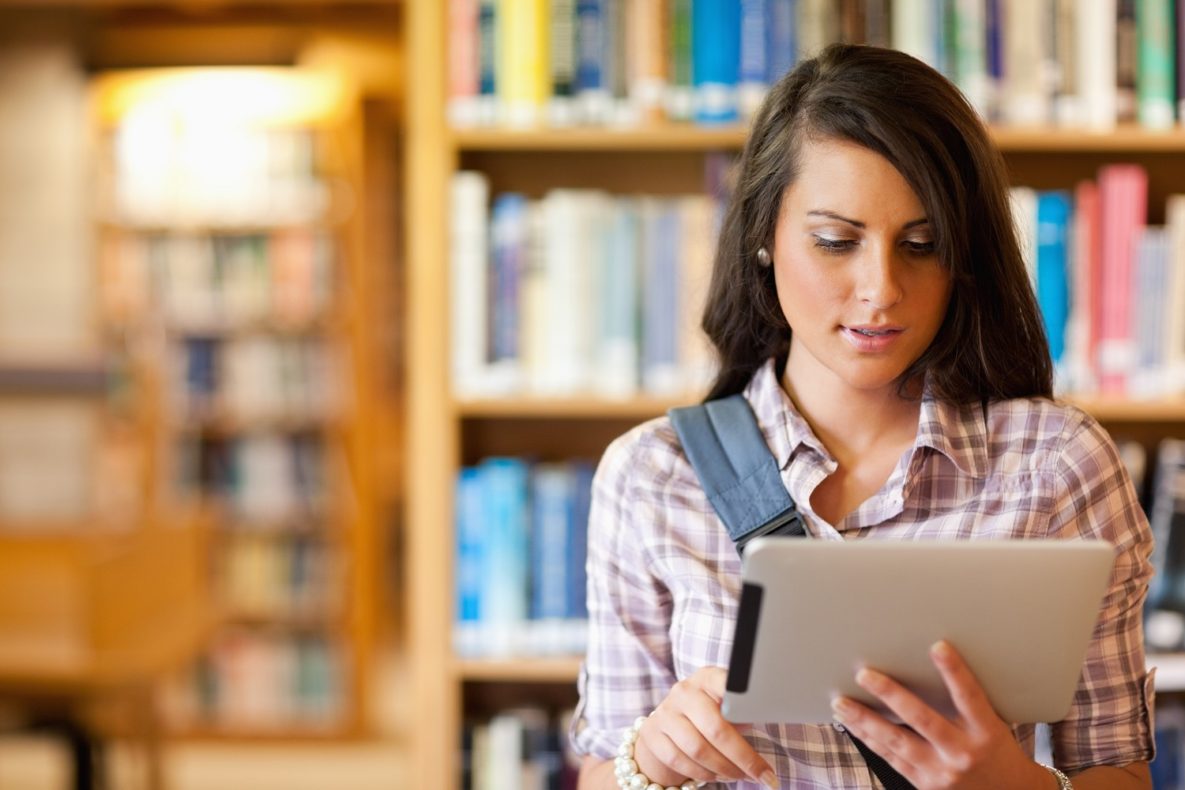 A young woman using a tablet in the library.