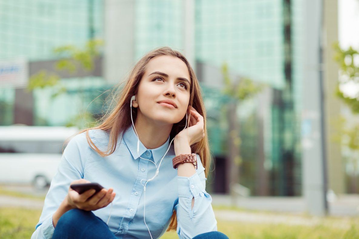 A woman using headphones to listen to her smartphone.
