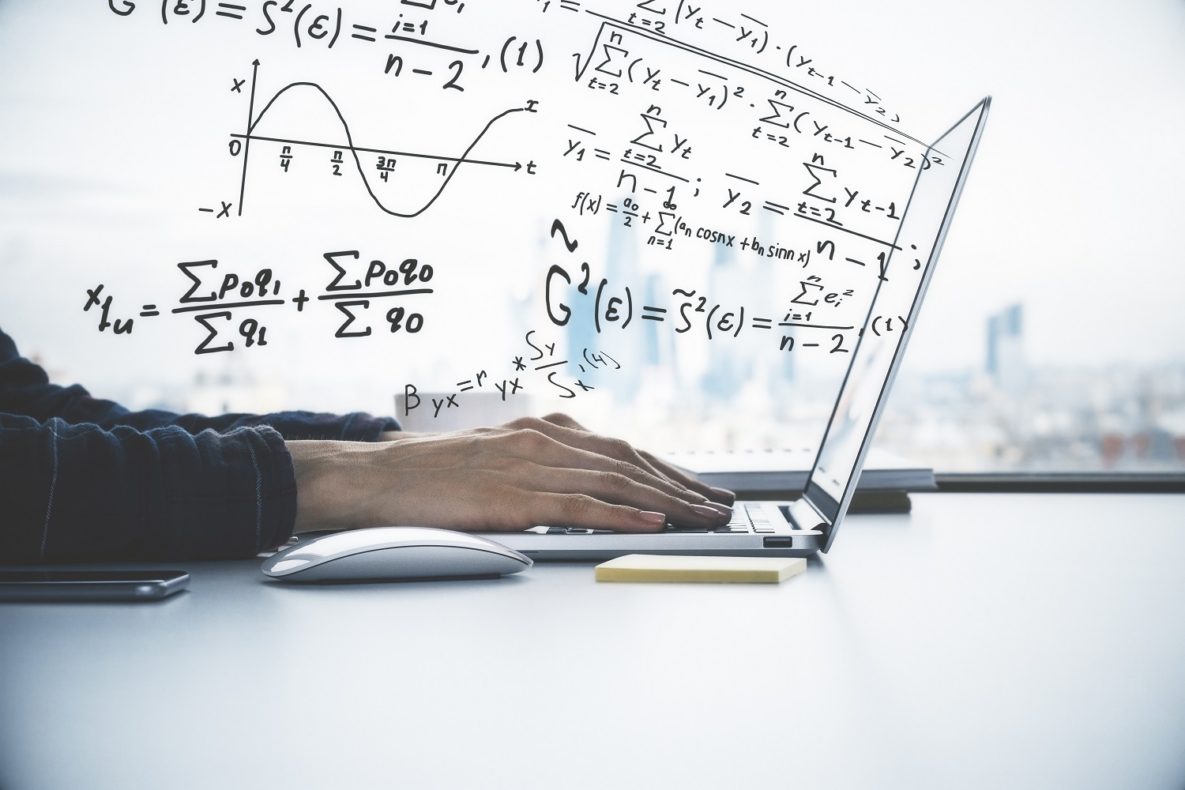 Hands typing on laptop with math equations in foreground.