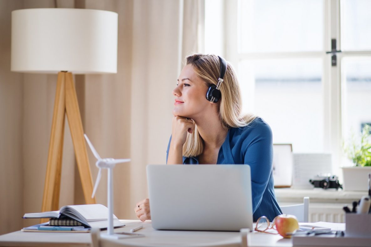 A working woman using a laptop with headphones on.