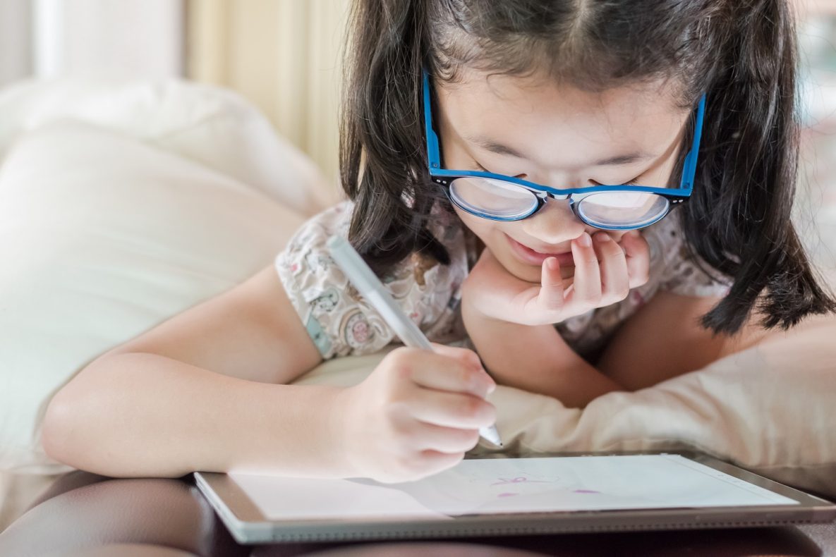 A young girl doing math on a tablet.
