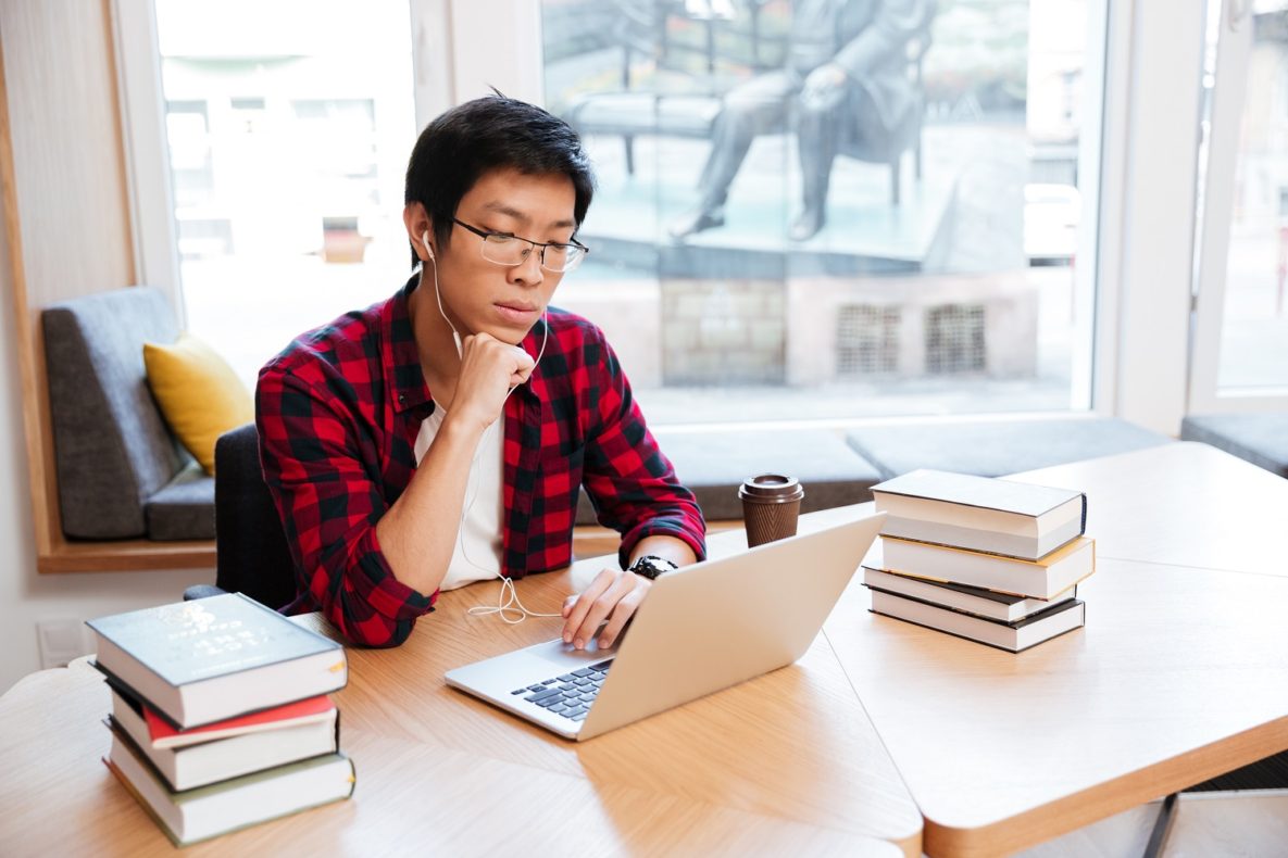 A man using a laptop and headphones to study.