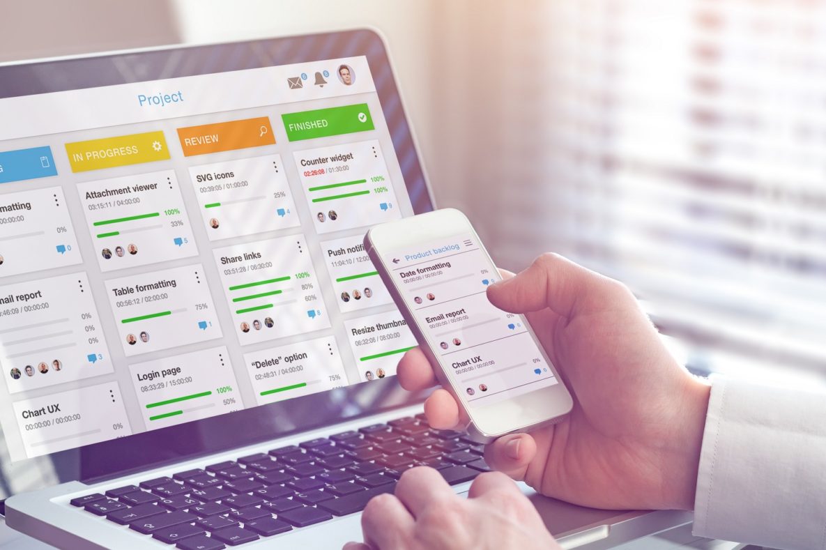 A person using a task management app on their smartphone and laptop.