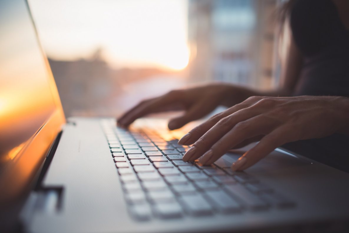 A close-up shot of someone writing on their laptop.