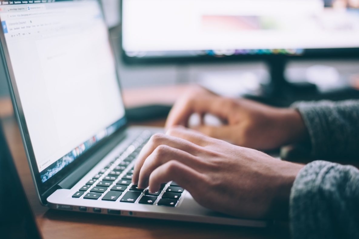 A close-up shot of someone writing on their laptop.