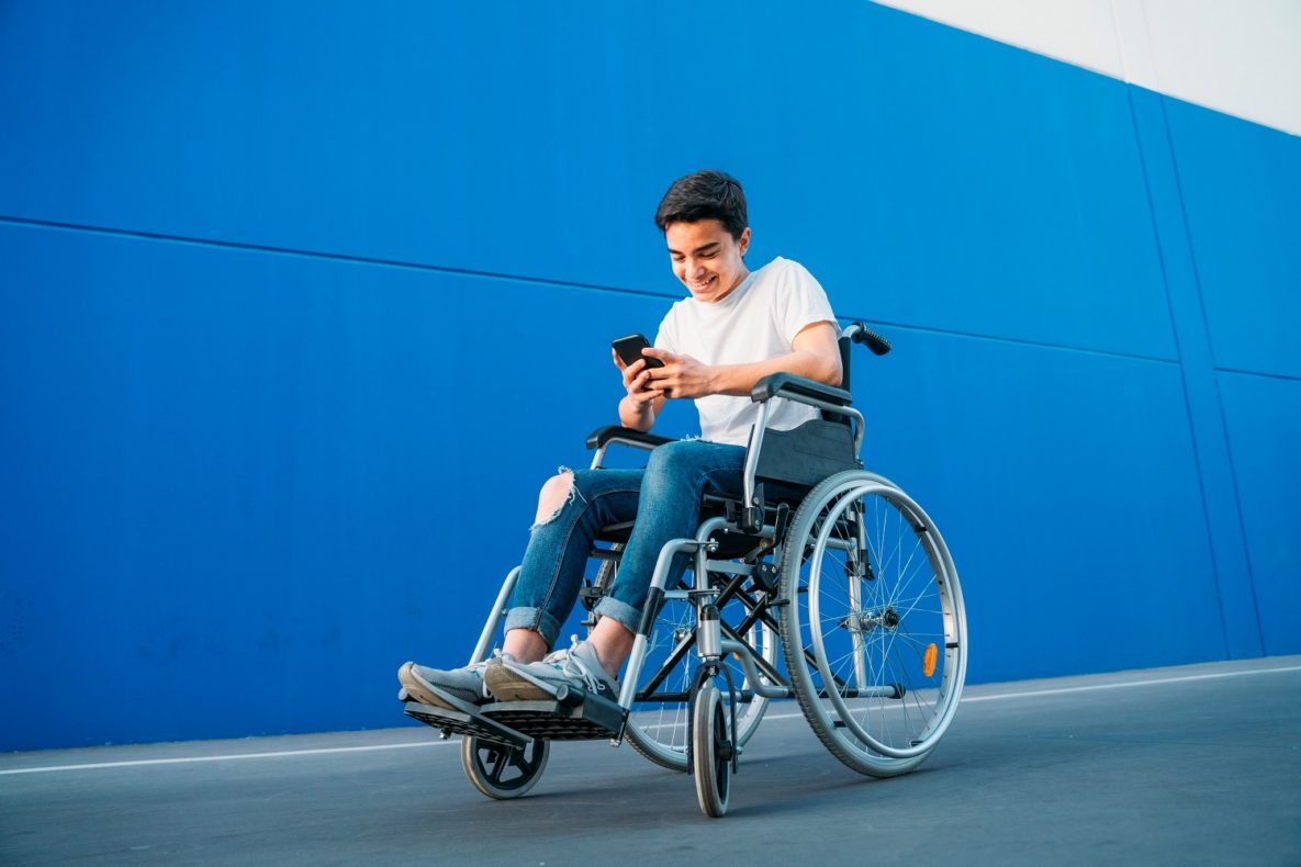 A young man in a wheelchair using his smartphone.