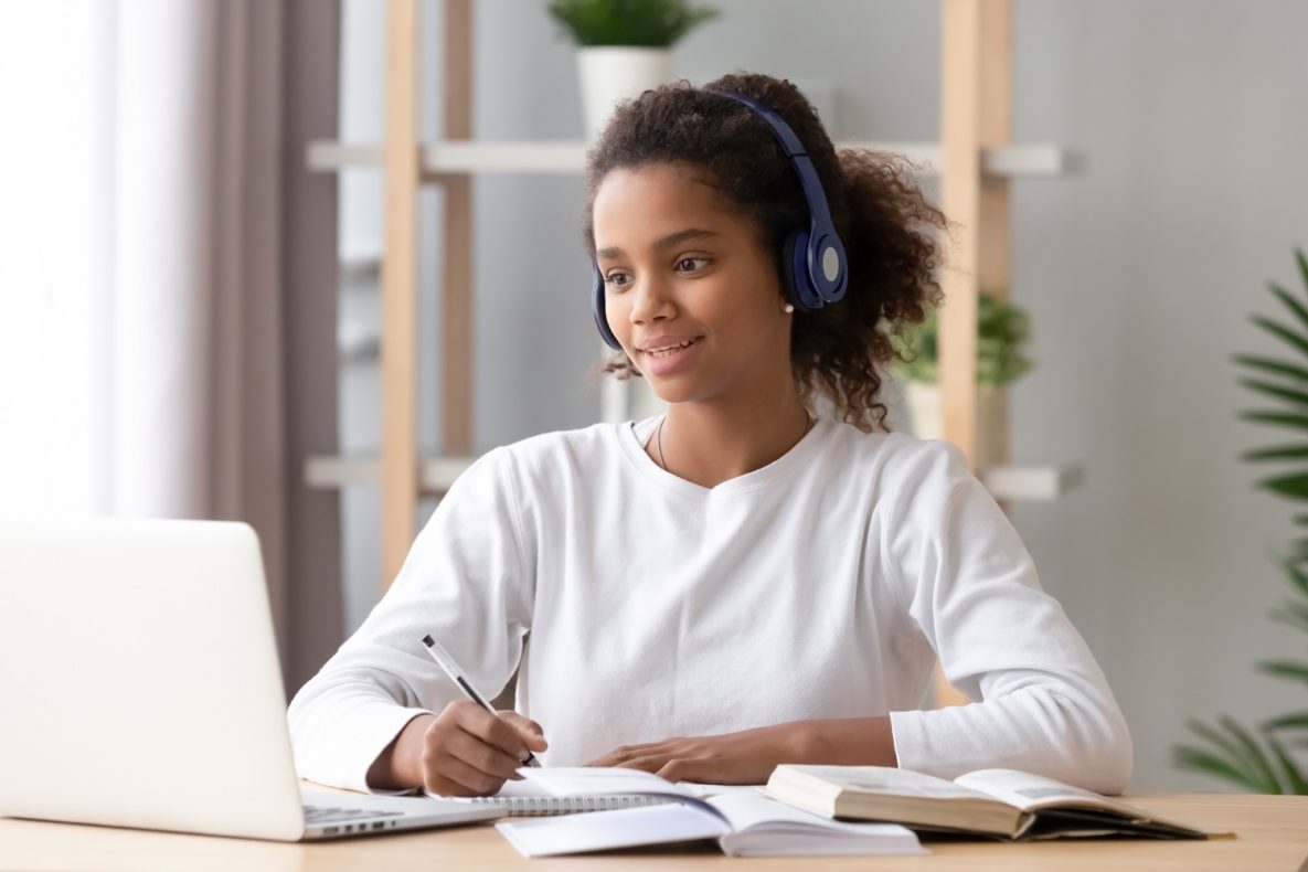 A young woman using headphones and a laptop to study.
