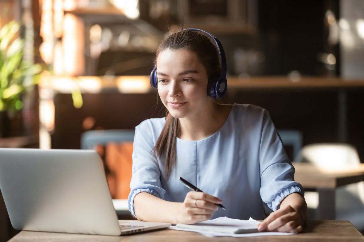 A woman using a laptop with headphones on.
