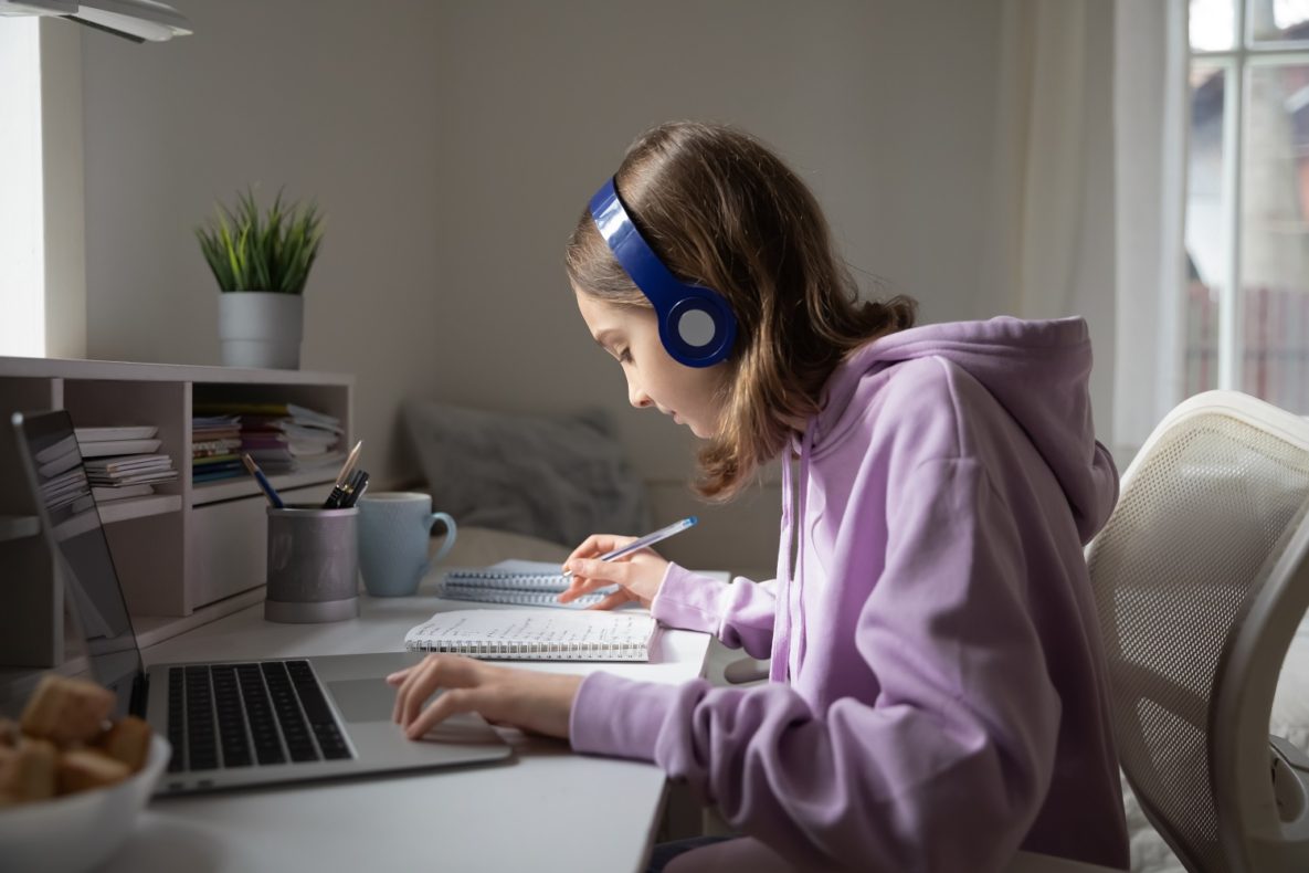 A young woman using headphones and a laptop to study.
