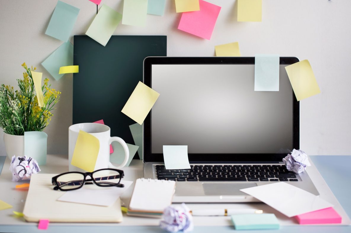 A computer with sticky notes attached.