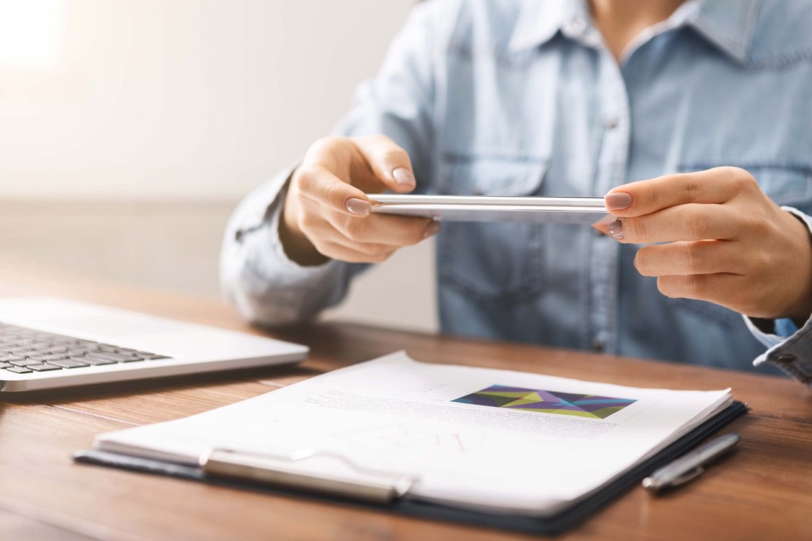 A woman using a smartphone to scan a document.