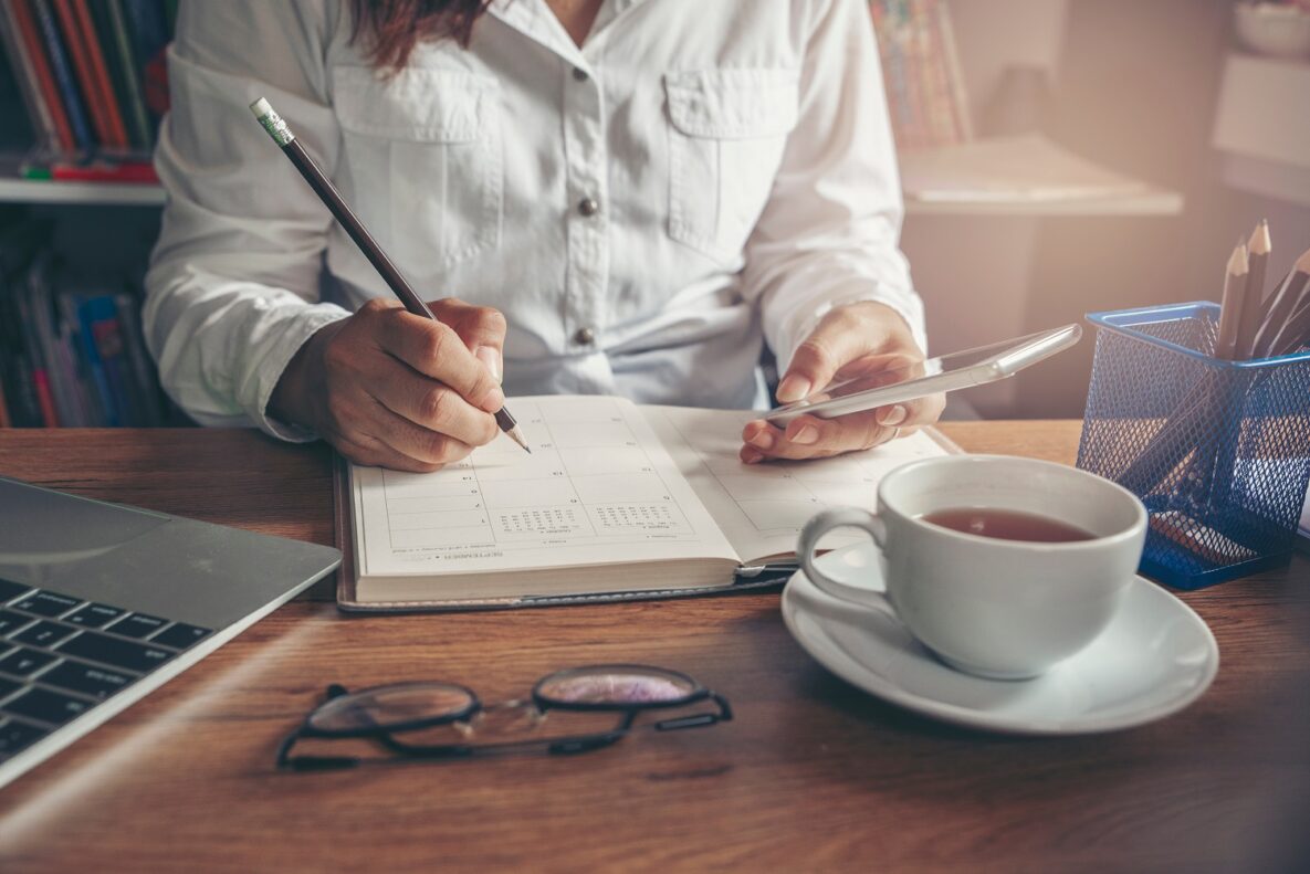 A woman using a calendar and smart phone.