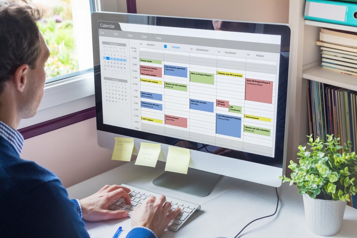 A man on his computer using a calendar.