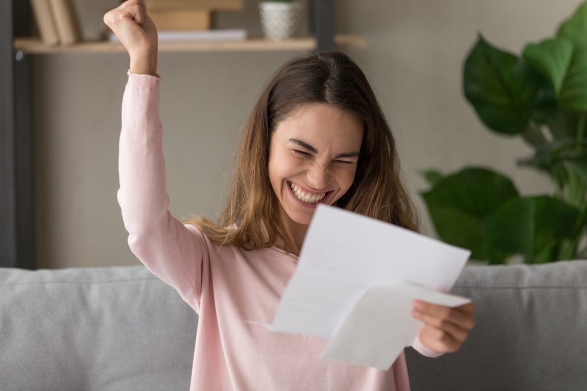 An excited woman holding a piece of paper.