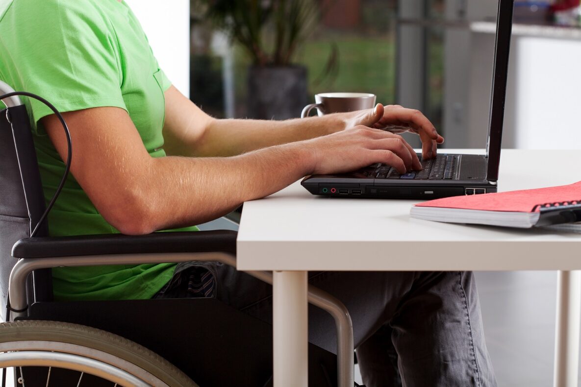 A man in a wheelchair using his laptop.