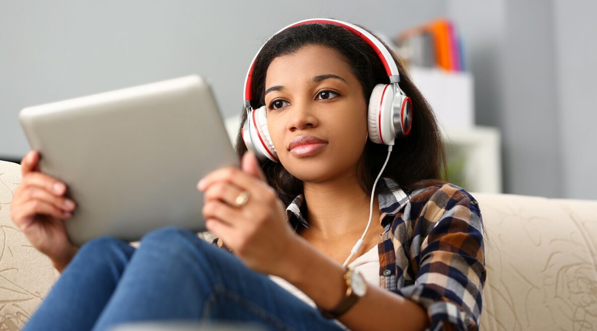 A young woman with headphones using her tablet.