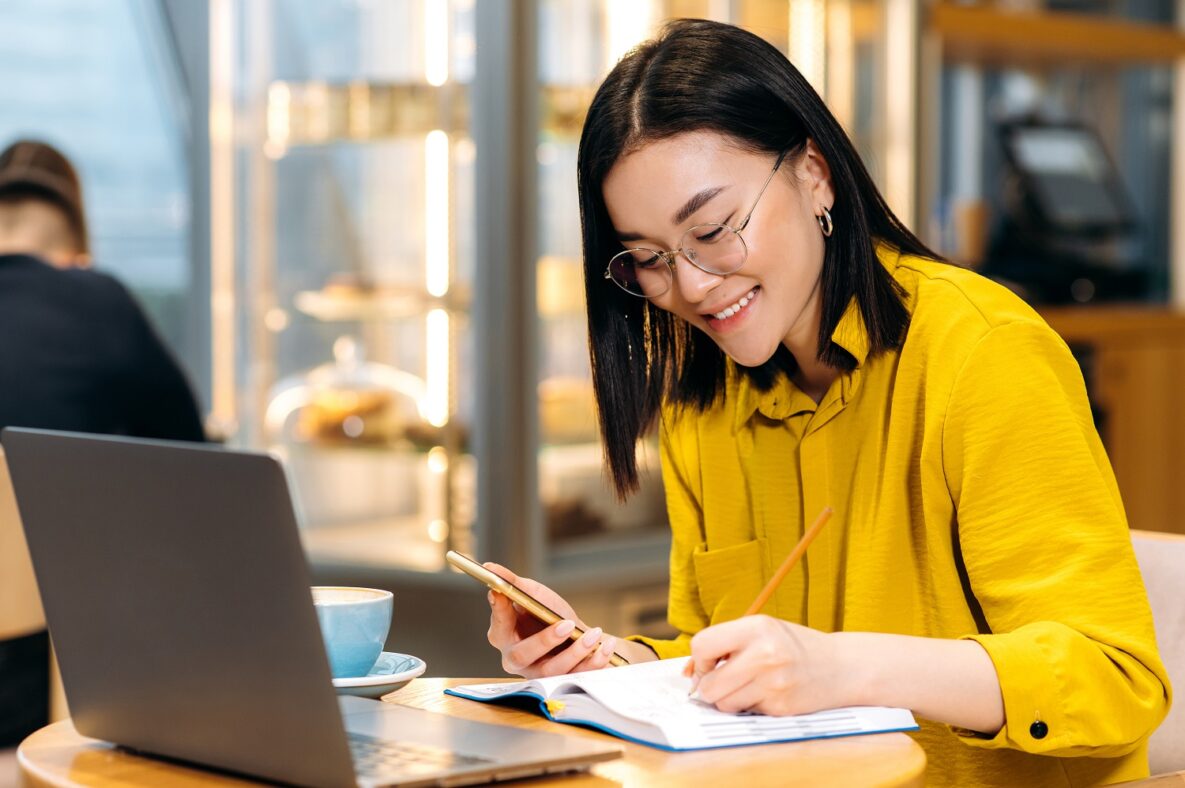 A woman working with her laptop and smartphone.