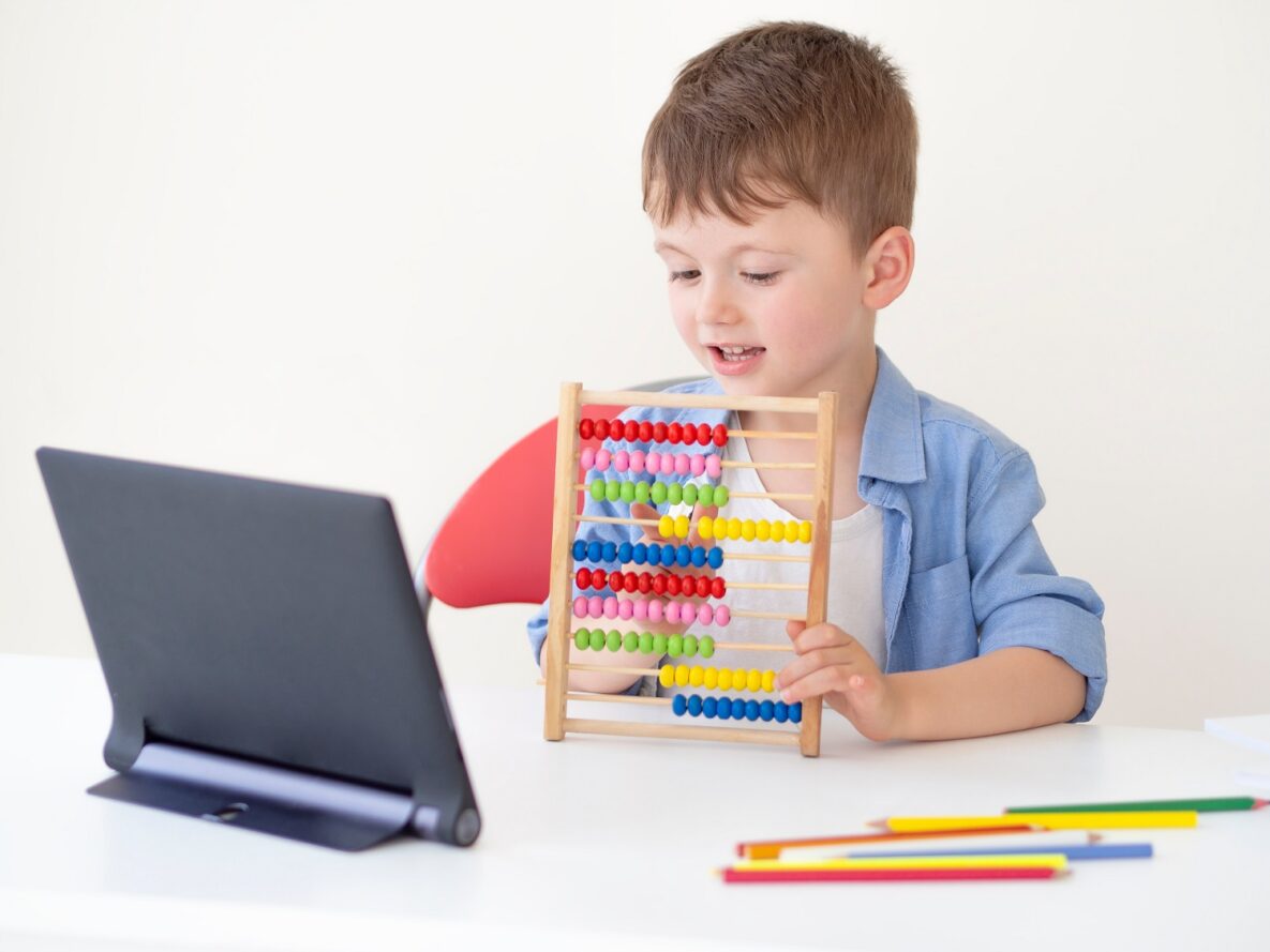A young boy using an abacus and a tablet.