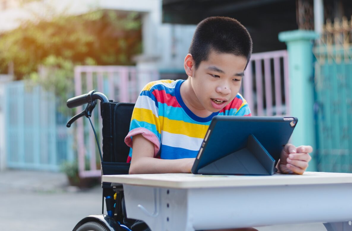 A young boy in a wheelchair using his tablet to study.