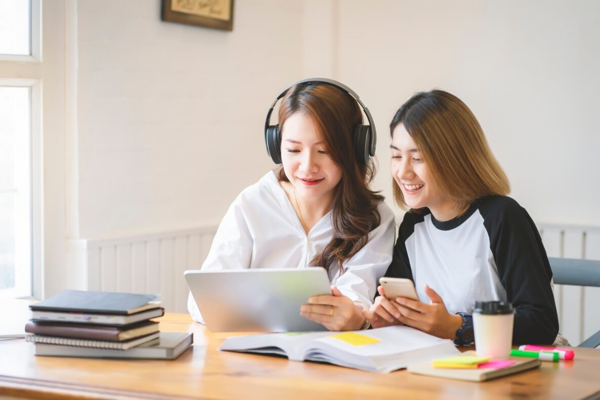 Two women using their devices to study.