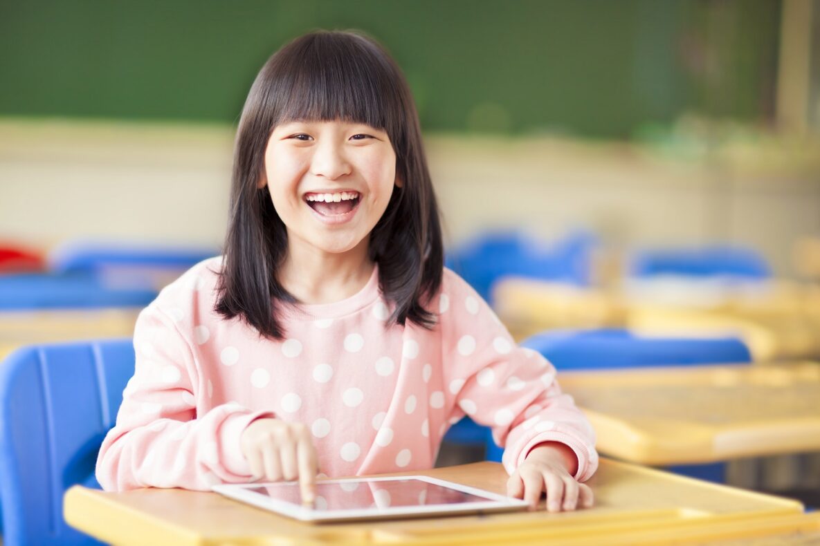 A young girl using her tablet in class.