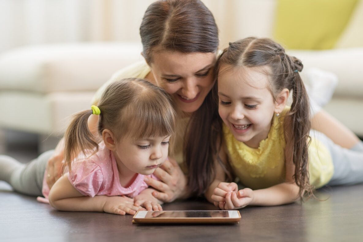 A mom and her daughters using a tablet.
