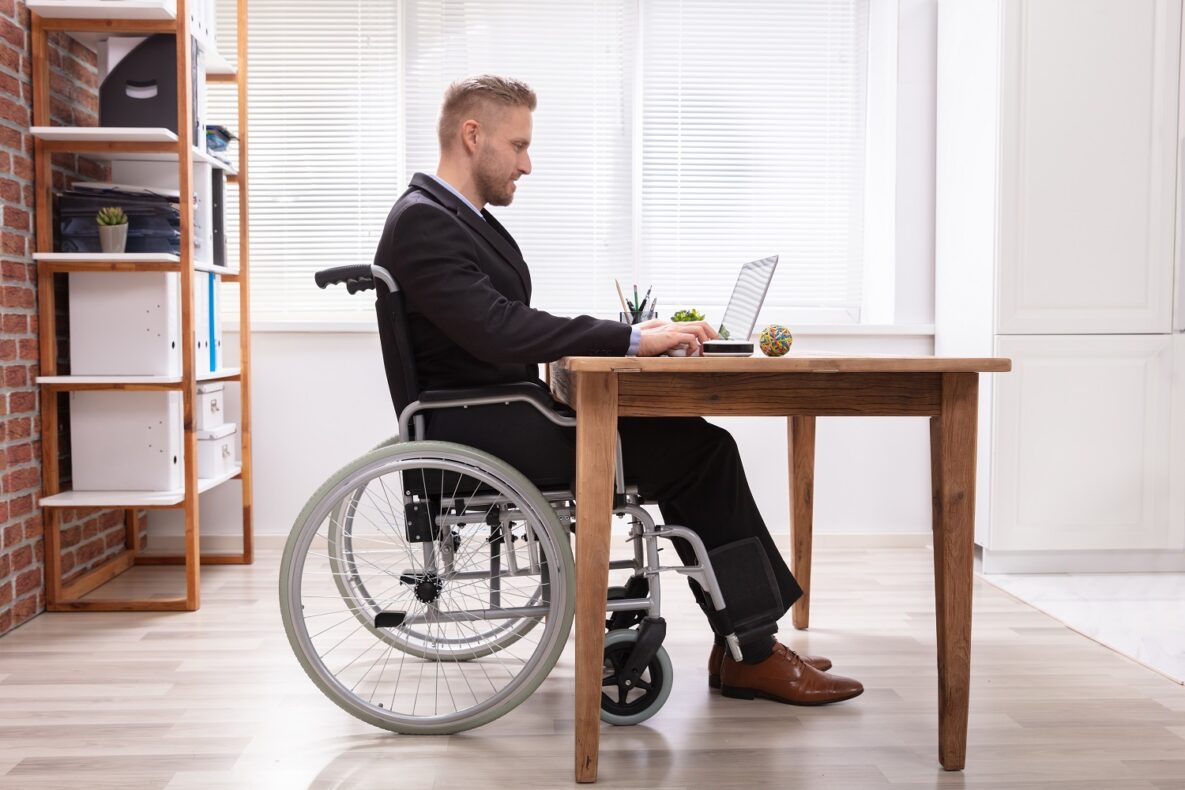 A man in a wheelchair using his laptop at work.