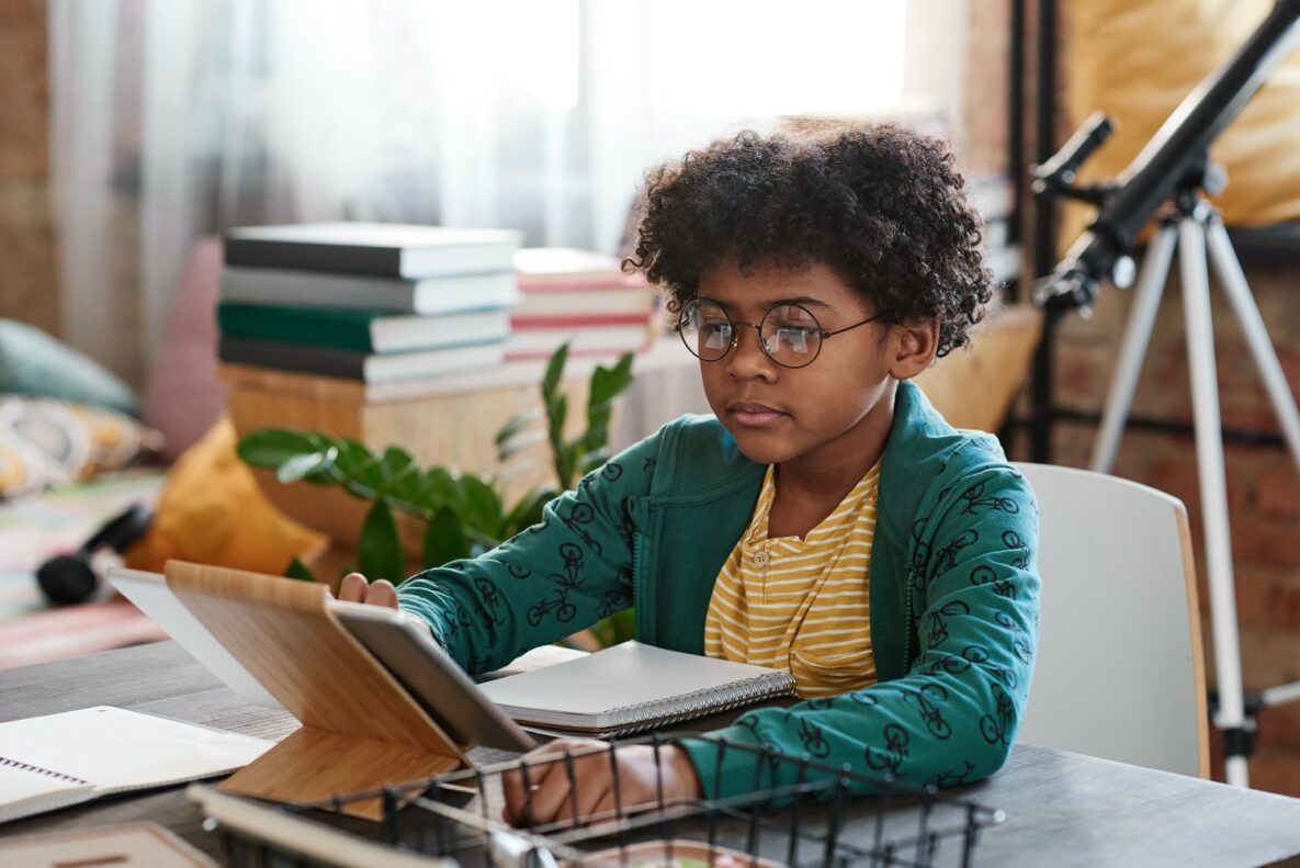 A little boy using a tablet in his study