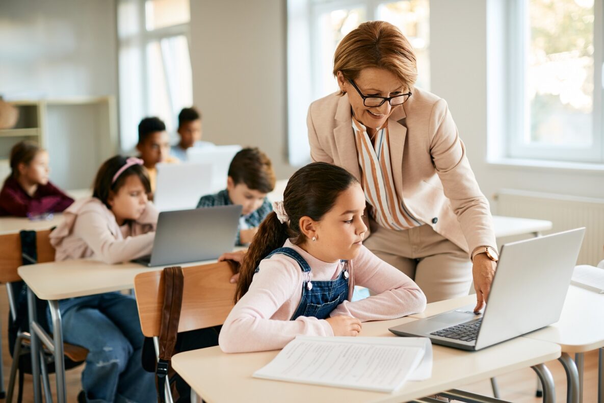 A teacher and her student using a laptop in the classroom.