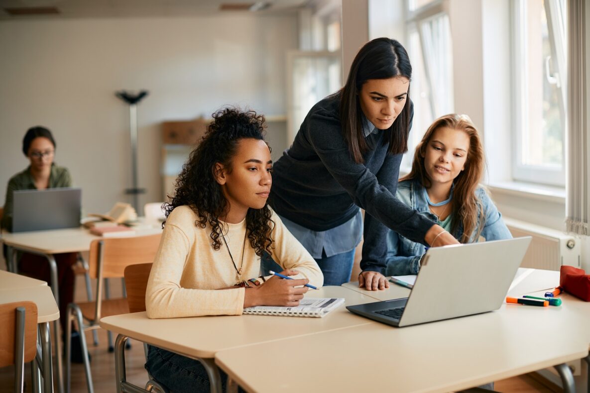 A teacher and her students using a laptop in class.