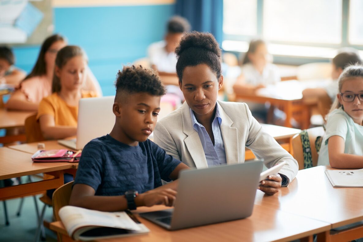 A teacher and her student using a laptop in class.