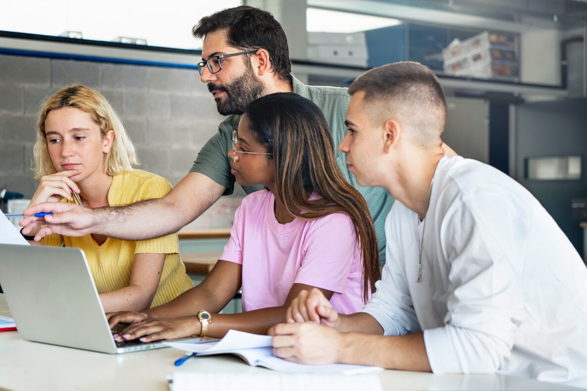 A teacher and his students using a laptop in class.