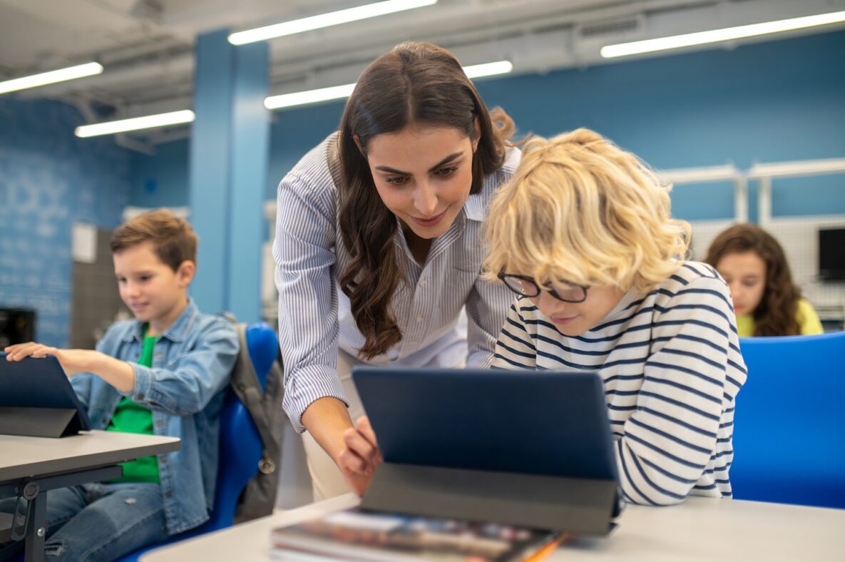 A teacher and student using a tablet in a classroom.