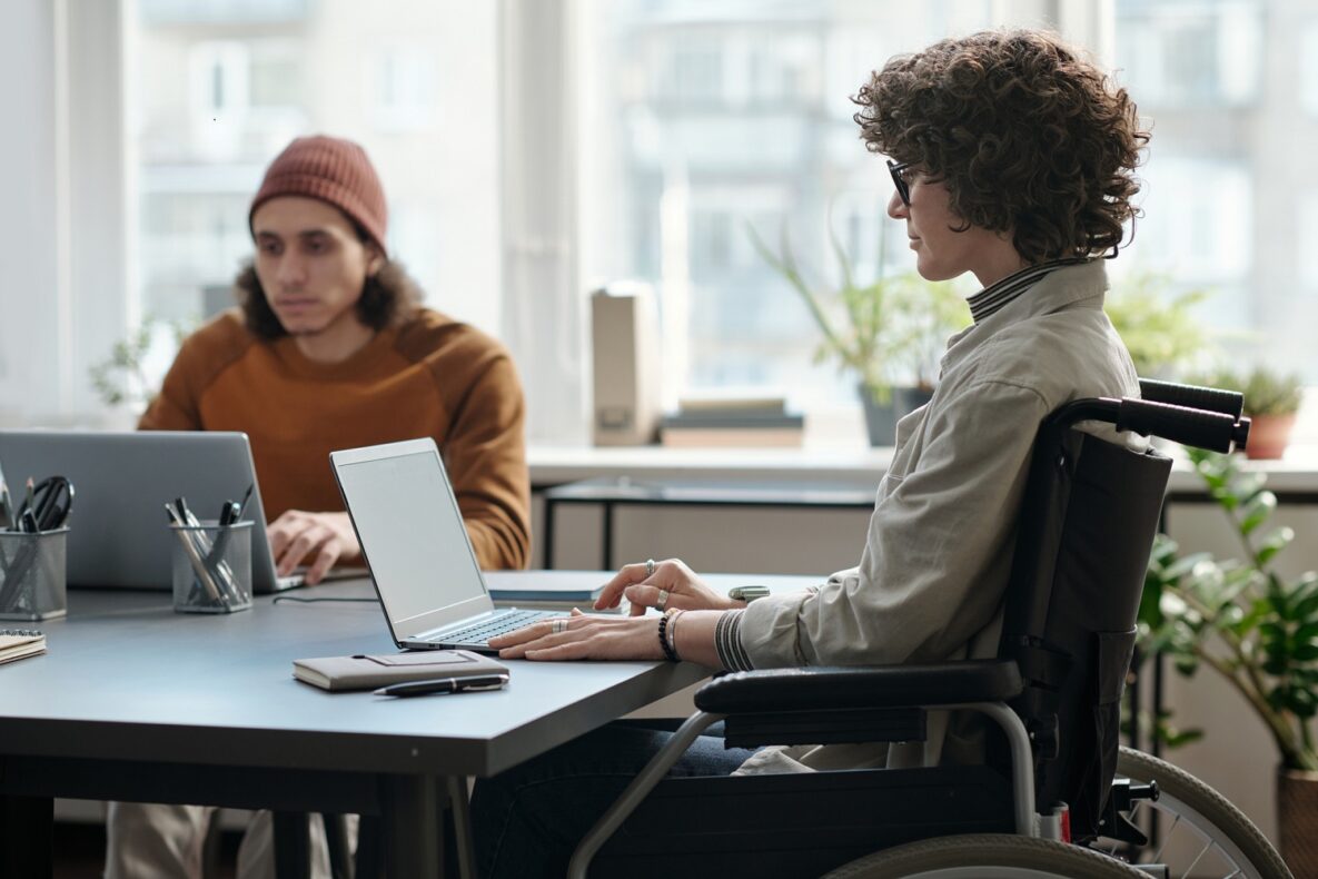 A young woman sitting in her wheelchair in front of her laptop.