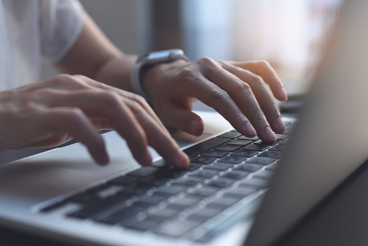 A close up of someone typing on their laptop.