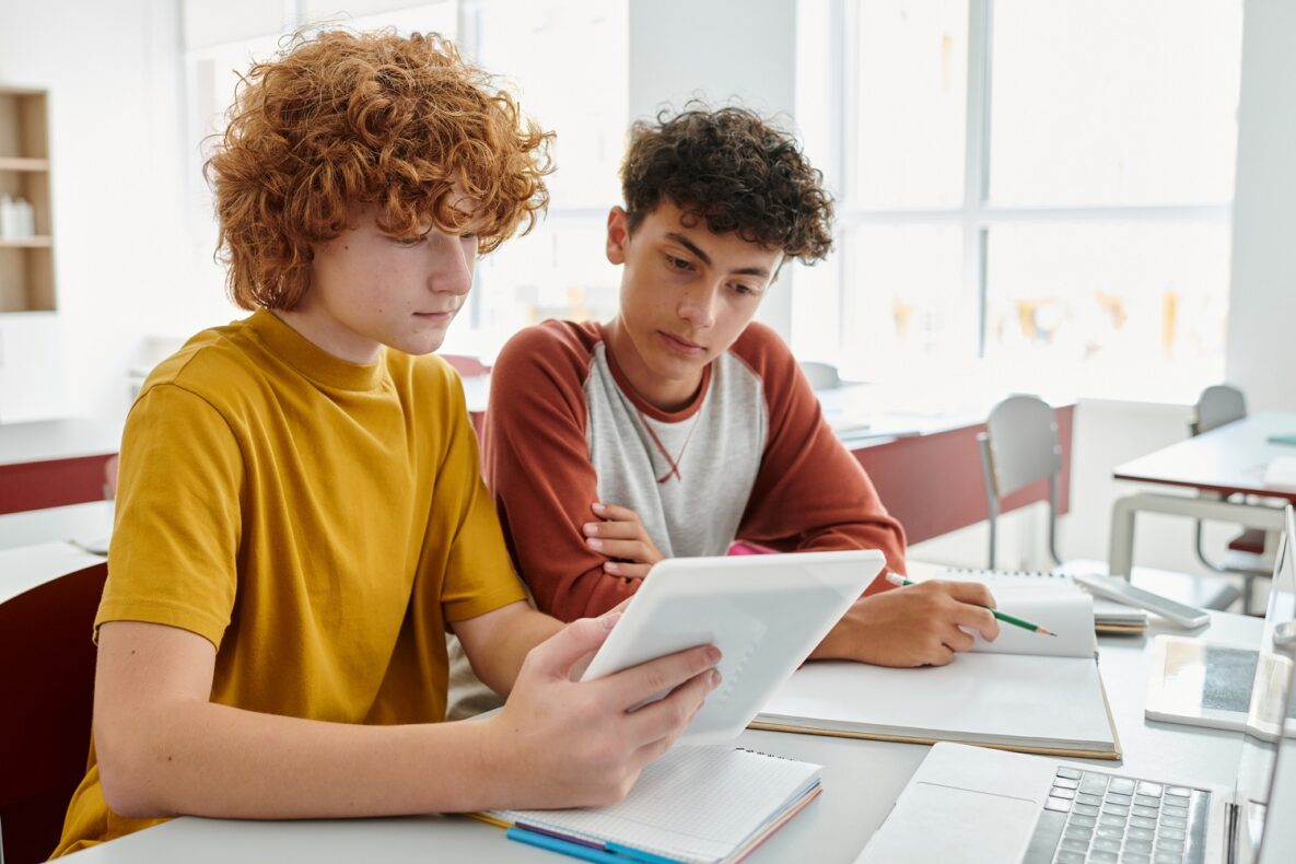 Two students focus intently on a tablet